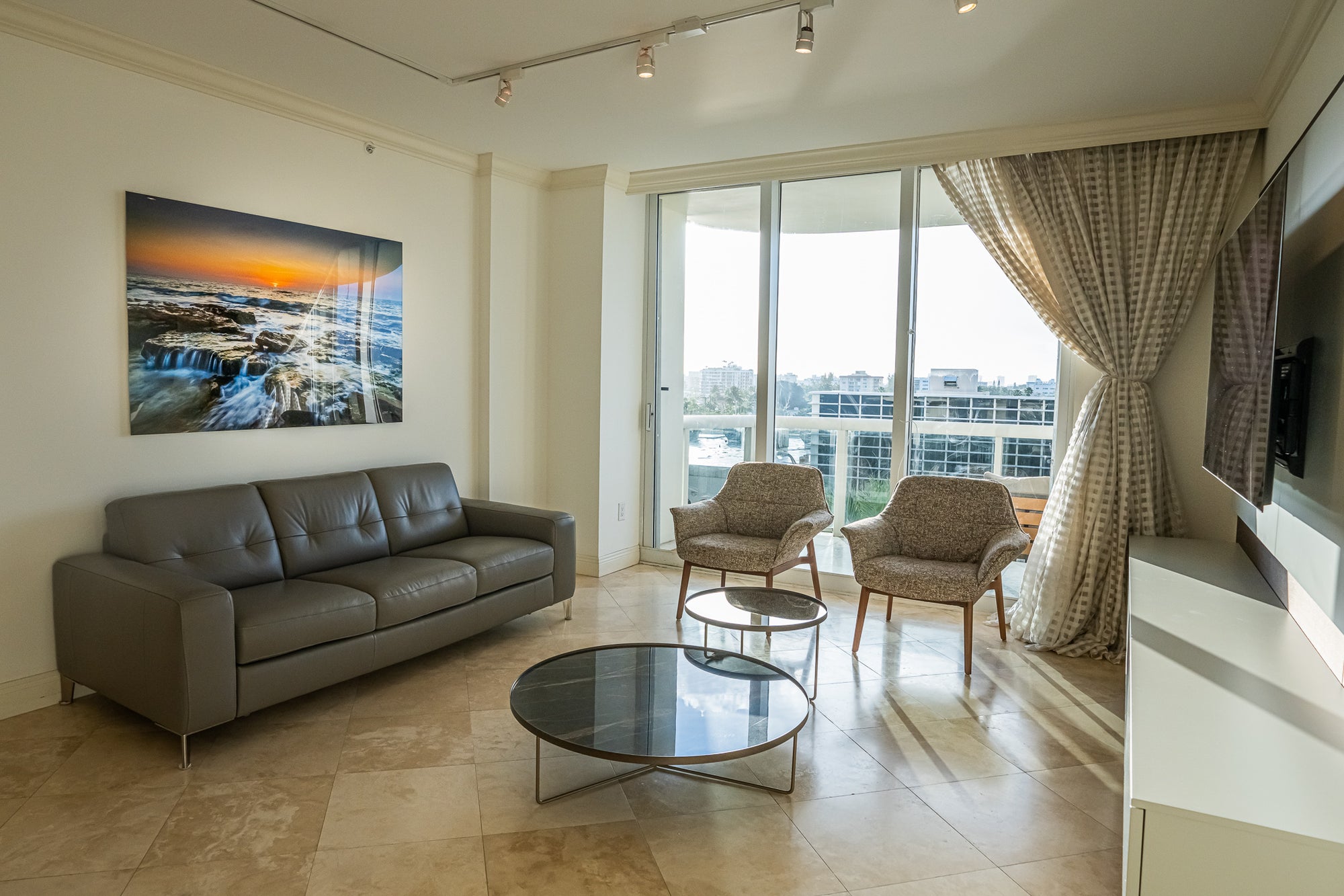 A sea-rocks sunset piece above a leather sofa
